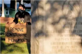  ?? MAX GERSH / THE COMMERCIAL APPEAL ?? Jeffrey Opp of Memphis holds a sign while sitting near the United Daughters of the Confederac­y marker Sunday at City Square Park in Colliervil­le, Tenn.