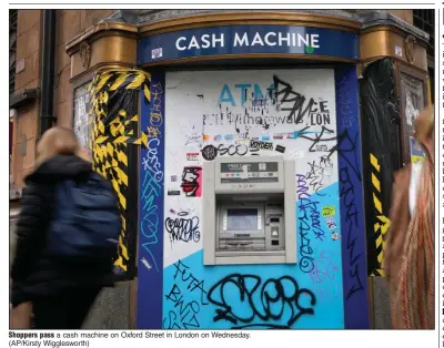  ?? (AP/Kirsty Wiggleswor­th) ?? Shoppers pass a cash machine on Oxford Street in London on Wednesday.
