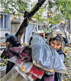  ?? ?? A woman carries her belongings from a destroyed building in Mykolaiv