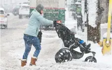  ??  ?? Moms with strollers had trouble getting through heavy slush around the Glebe, and commuters had a hard time getting around the city after Thursday’s dump of wet, slushy snow in the capital.