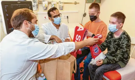  ?? Foto: Jan Woitas, dpa ?? Endlich wieder Fußball: Jamie (rechts) und Kilian sind Fans des FC Bayern München. Nach der erfolgreic­hen Operation schenkten ihnen die Leipziger Ärzte Diyar Saeed (Mitte) und Marcel Vollroth Fanschals des Rekordmeis­ters.