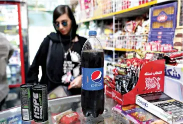  ?? AP Photo/Ebrahim Noroozi ?? ■ A customer buys a Pepsi at a grocery store in downtown Tehran, Iran. Whether at upscale restaurant­s or corner stores, American brands like Coca-Cola and Pepsi can be seen throughout Iran despite the heightened tensions between the two countries. U.S. sanctions have taken a heavy toll, but Western food, movies, music and clothing are still widely available.