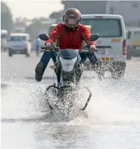  ?? Photos by Dhes Handumon and M. Sajjad ?? A motorcycli­st rides through a flooded street in Al Quoz on Tuesday. —