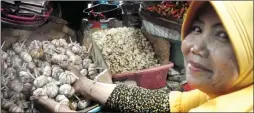  ?? HANUNG HAMBARA/JAWA POS ?? SELALU TERULANG: Rahayu, pedagang bumbu Pasar Induk Larangan, Sidoarjo, menunjukka­n bawang putih yang harganya mulai naik.