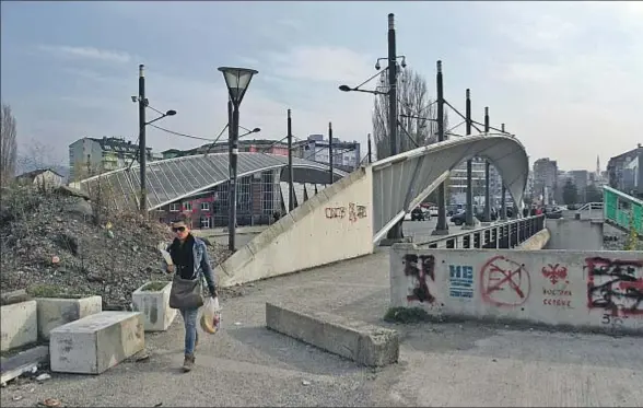  ?? DJORDJE SAVIC / EFE ?? Una mujer cruza el puente de la población kosovar de Mitrovica, que conecta el norte y el sur y marca la división étnica, en una imagen de archivo