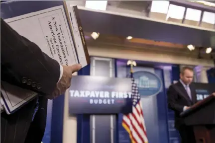  ?? AP PHOTO/ANDREW HARNIK ?? A staff member holds a binder that reads “A New Foundation for American Greatness Took Kit for Communicat­ors” as Budget Director Mick Mulvaney (right), pauses while speaking to the media about President Donald Trump’s proposed fiscal 2018 federal...