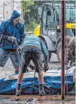  ??  ?? Das pitschnass­e Ende: Die Helfer beim Abbau des Theaterfes­tivalZelts stehen im Regen.