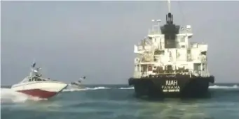  ?? AP ?? HIGH SEAS DRAMA: Photo provided by Iranian state television shows the UAE-based oil tanker MT Riah being surrounded by Iranian Revolution­ary Guard vessels in the Strait of Hormuz. At right, the seized ship in a photo captured off video released by the guard Thursday.