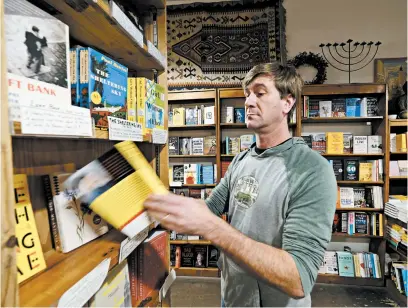  ?? ERIC RISBERG/AP ?? Pete Mulvihill looks over one of the books on display at his Browser Books store that he recently opened in San Francisco.