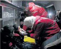  ?? HAMZA AL- AJWEH/ GETTY IMAGES ?? Members of the Syrian Arab Red Crescent tend to Syrian girls in an ambulance in Douma on the third night of evacuation­s from the besieged rebel enclave of eastern Ghouta, on the outskirts of the Damascus.