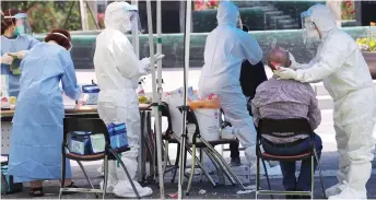  ?? — AFP photo ?? Health workers wearing protective gear take samples from a visitor for the Covid-19 coronaviru­s test at a temporary virus testing centre in Seoul.