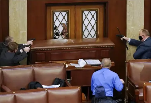  ?? ?? U.S. Capitol police officers aiming their weapons at the main door of the House Chamber, while members of a mob supporting U.S. President Donald Trump try to gain entry. Drew Angerer/Getty Images