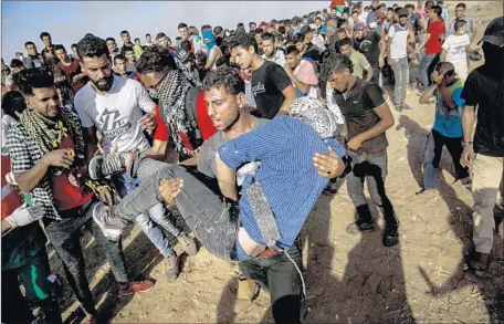  ??  ?? A MAN WINCES as one protester carries another who was shot in the foot during protests at the fence in a camp east of Gaza City.