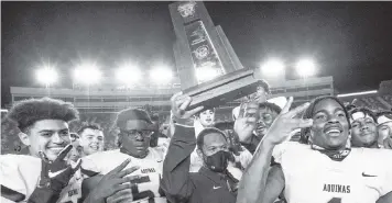  ?? DANIEL A. VARELA dvarela@miamiheral­d.com ?? St. Thomas coach Roger Harriott holds up the Class 7A championsh­ip trophy as he celebrates on the field with his players after defeating Edgewater at Doak Campbell Stadium in Tallahasse­e on Saturday.