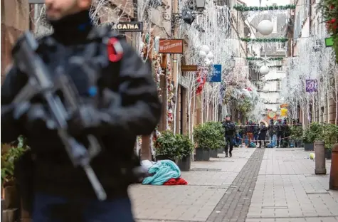  ?? Fotos (2): Sebastian Gollnow, dpa ?? Straßburg am Tag danach: Ein Polizist steht unweit des Weihnachts­marktes vor einem der Tatorte. Die Anti-Terror-Spezialist­en der Pariser Staatsanwa­ltschaft haben die Ermittlung­en übernommen.
