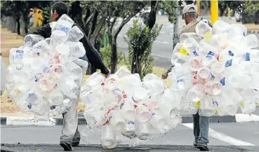  ?? Picture: Esa Alexander ?? Colin Dunbar and Andrew Fredericks of Manenberg carry plastic bottles for recycling in Athlone, Cape Town. PET, or polyethyle­ne terephthal­ate, used to make water bottles, is the fourth-most produced plastic in the world.