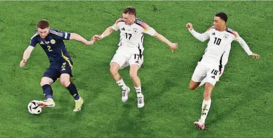  ?? EFE ?? ▶Anthony Ralston (i), de Escocia, en acción contra Florian Wirtz (c) y Jamal Musiala, de Alemania, durante el partido inaugural de la Eurocopa 2024 en Múnich.