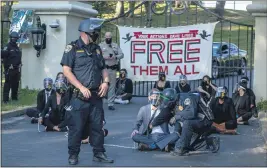  ?? DANIEL KIM. — THE SACRAMENTO BEE VIA AP ?? A California Highway Patrol officer inspects a chained protester outside of California Gov. Gavin Newsom’smansion in Fair Oaks on July 27.