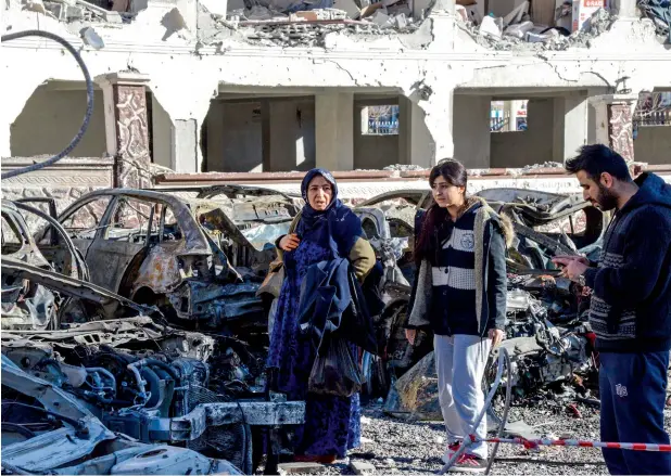  ?? —AFP ?? Despite raging on for more than six years, there is no end in sight for war in Syria and parties are going around in circles. In this picture, people walk past damaged cars at the blast site in Sanliurfa.
