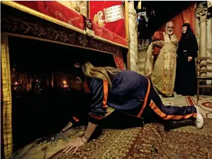  ?? AFP ?? A Christian worshipper touches a silver star, believed to be the exact spot where Jesus Christ was born, in the grotto of Bethlehem’s Church of the Nativity on Tuesday. —