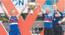  ?? Picture: MARK STEWART ?? Triumphant Western Bulldogs players Ellie Blackburn and Katie Brennan raise aloft the premiershi­p cup after their win over the Lions yesterday
