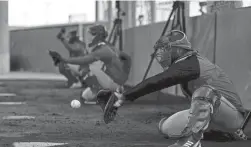  ?? SAM GREENE/CINCINNATI ENQUIRER/USA TODAY SPORTS ?? Pitchers and catchers work in the bullpen at the Reds Player Developmen­t Complex in Goodyear.