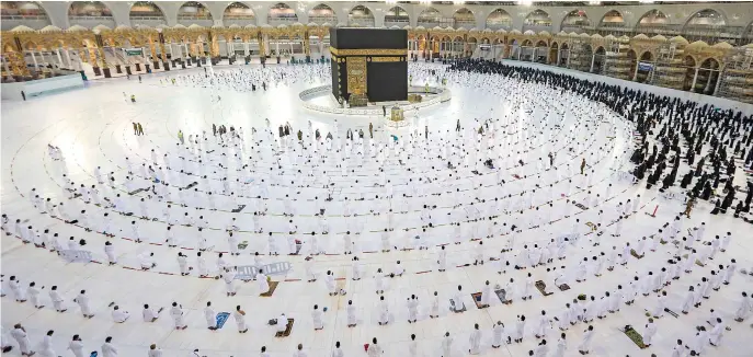  ?? Reuters ?? Umrah pilgrims, keeping a safe social distance, offer prayers in the Grand Mosque in Makkah. Saudi Arabia is gradually lifting restrictio­ns imposed following the outbreak of the coronaviru­s pandemic.