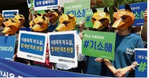  ?? — AFP ?? Save the dogs: South Korean animal rights activists wearing dog-shaped masks outside a court in Seoul as they rally in support of the new ruling.