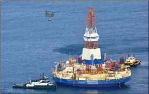  ?? The Associated Press ?? RISKY BUSINESS: In this Jan. 7, 2013, file photo, a U.S. Army CH-47 Chinook helicopter flies over the Kulluk, a Shell floating drill rig off Kodiak Island in Alaska’s Kiliuda Bay, as salvage teams conduct an in-depth assessment of its seaworthin­ess...