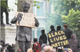  ?? Justin Tallis / AFP/ Getty Images ?? A statue of former South African President Nelson Mandela is adorned with a Black Lives Matter placard in Parliament Square in central London.