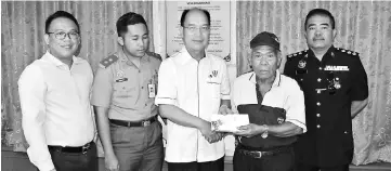  ??  ?? Kendawang Onggie of Rumah Adam receives his flood aid from Gerawat (centre) witnessed by (from left) SAO Reagan, Mirwan and ASP Jaimi.