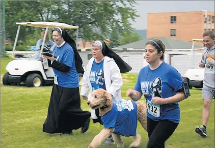  ?? SISTERS OF ST. FRANCIS ?? Sister Cindy Drozd, center, and her dog, Buddy, and other runners participat­e last year in Run with the Nuns, a fundraiser race benefiting the Sisters of St. Francis of Christ the King in Lemont.