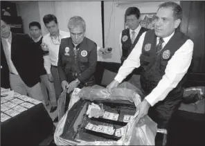  ?? AP/KAREL NAVARRO ?? A police officer shows stacks of counterfei­t U.S. $100 notes to reporters in Lima, Peru, in August 2012. Counterfei­ting in Peru has grown as U.S. anti-drug policies have cracked down on neighborin­g Colombia, with counterfei­ters earning up to $20,000 in...