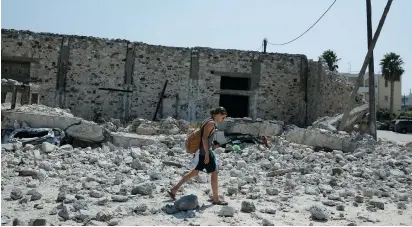  ?? (Reuters) ?? A MAN WALKS among debris following an earthquake on the island of Kos, Greece on Friday.
