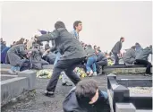 ??  ?? Following a grenade attack, people take shelter on the ground in Milltown cemetery in Belfast, left, during the funeral, right, for three IRA members in March 1988, who were killed in Gibraltar by the SAS
