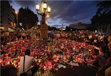  ?? Emilio Morenatti / Associated Press ?? Candles and flowers are placed on the ground Sunday in Barcelona, Spain, at the scene of a terrorist attack.