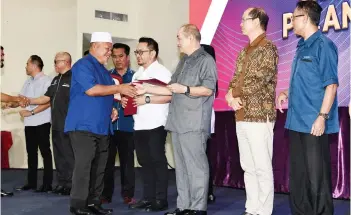  ?? ?? Chief Minister Datuk Seri Panglima Haji Hajiji Haji Noor presenting the appointmen­t letter to one of the JKKK chairmen at Dewan Seri Sulaman on Wednesday.