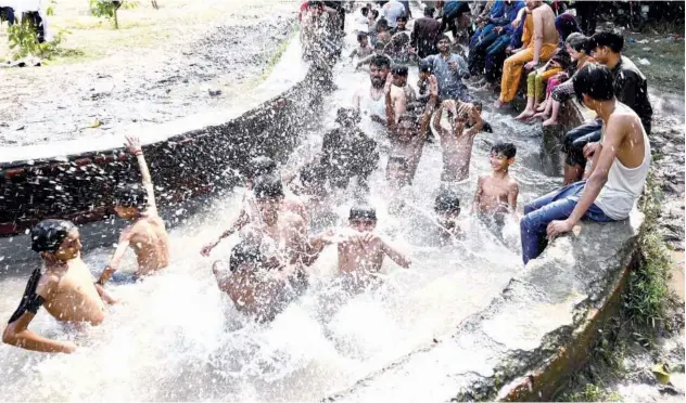  ?? ?? ↑
People cool themselves in a canal on a hot summer day in Lahore on Friday. Agence France-presse