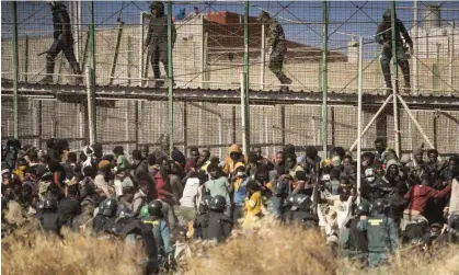  ?? Photograph: Javier Bernardo/AP ?? Riot police cordon off the area after people arrive on Spanish soil after crossing the fences separating Melilla from Morocco in June.