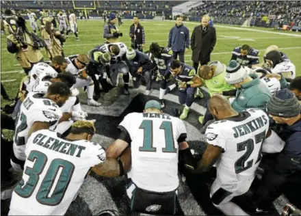  ?? TED S. WARREN — THE ASSOCIATED PRESS ?? Members of the Philadelph­ia Eagles and Seattle Seahawks join in prayer of their game this season.