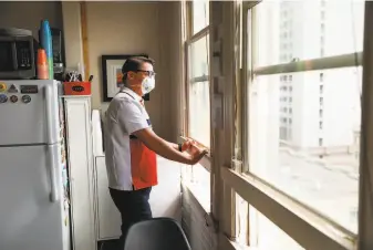  ??  ?? Curtis Bradford, a community organizer who is HIVpositiv­e and has been told by his doctor not to venture out in the neighborho­od, looks out his window in his Alexander Residence room.