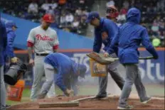  ?? MARK LENNIHAN — THE ASSOCIATED PRESS ?? Phillies pitcher Vince Velasquez watches as the New York Mets’ grounds crew works on the pitcher’s mound during a light rain in the first inning of Sunday’s game at Citi Field. It didn’t help. The Mets beat Valasquez and the Phils, 6-4.