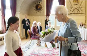  ?? Joe Giddens/Associated Press photos ?? Britain’s Queen Elizabeth II receives a bouquet from Harriet Reeve, 9, during a reception to celebrate the start of the Platinum Jubilee on Saturday at Sandringha­m House, her Norfolk residence, in Sandringha­m, England.