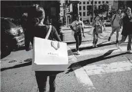  ?? DAVID PAUL MORRIS Bloomberg ?? A pedestrian carries a shopping bag in San Francisco on Sept. 29. Excluding gasoline, retail sales for September rose a tepid 0.1%.