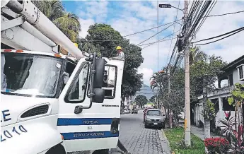  ??  ?? LABOR. Cuadrilla de la Enee instala lámparas en la calle principal de El Roble.