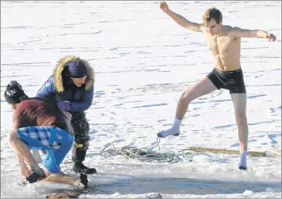  ?? BRIAN MCINNIS/THE GUARDIAN ?? Cheryl Paynter, left, organizer of the polar bear dip, helps a swimmer out of the water while an enthusiast­ic dipper takes a ‘swan dive’ into the icy waters.