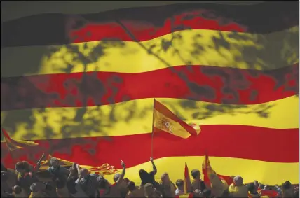  ?? AP PHOTO ?? A nationalis­t activist waves a Spanish flag in front of a giant Catalan flag during a mass rally against Catalonia’s declaratio­n of independen­ce in Barcelona, Spain.