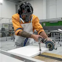  ?? JOSEPH JOHNSON/STUFF ?? A worker cuts an engineered stone bench top wearing a new health and safety standard uniform at Artisan Stone factory.