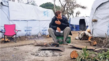  ??  ?? Ein Flüchtling wärmt sich im Auffanglag­er Moria auf Lesbos an einem Feuer.