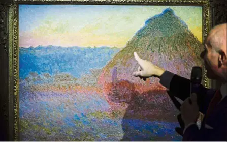  ??  ?? Conor Jordan, deputy chairman of impression­ist and modern art at Christie’s, pointing out details in Monet’s painting Meule during an auction preview in Hong Kong. — AFP